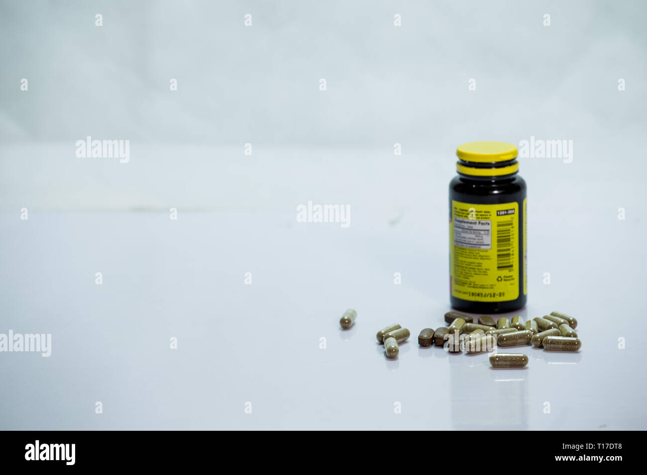 Drug bottle with capsules poured out with white background Stock Photo