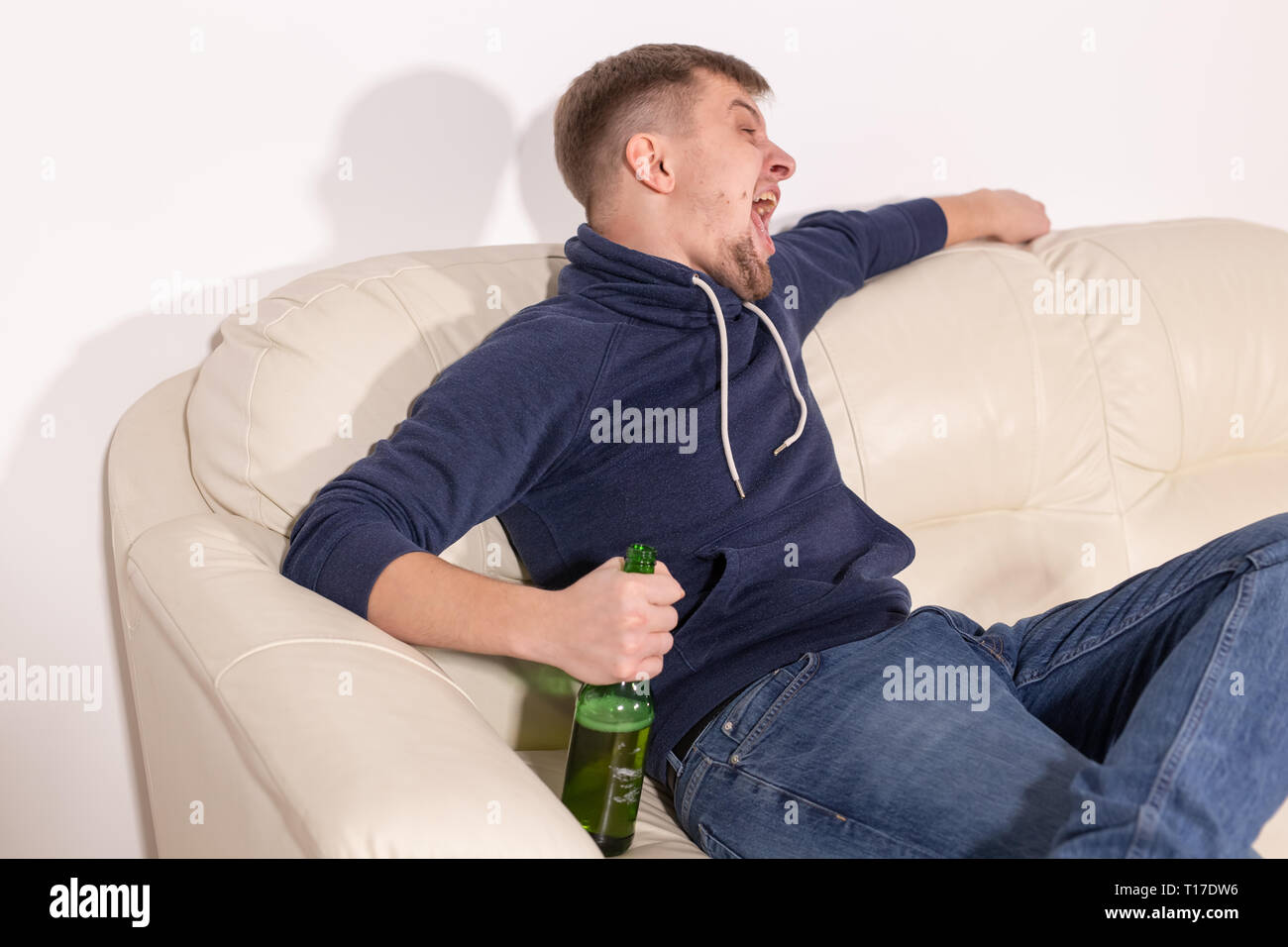Depression and alcoholism concept - Aggressive male alcoholic sitting on the sofa Stock Photo