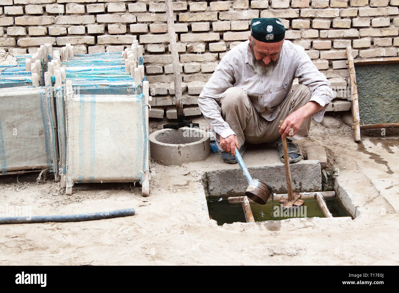 Old Uighur man mixing Mulberry bark ' soup ready to make paper sheets