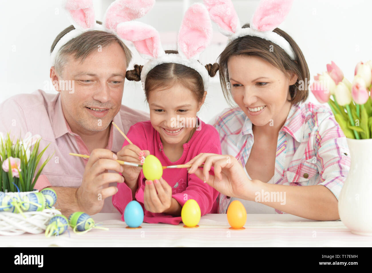 Portrait of parents with cute little daughter coloring eggs Stock Photo