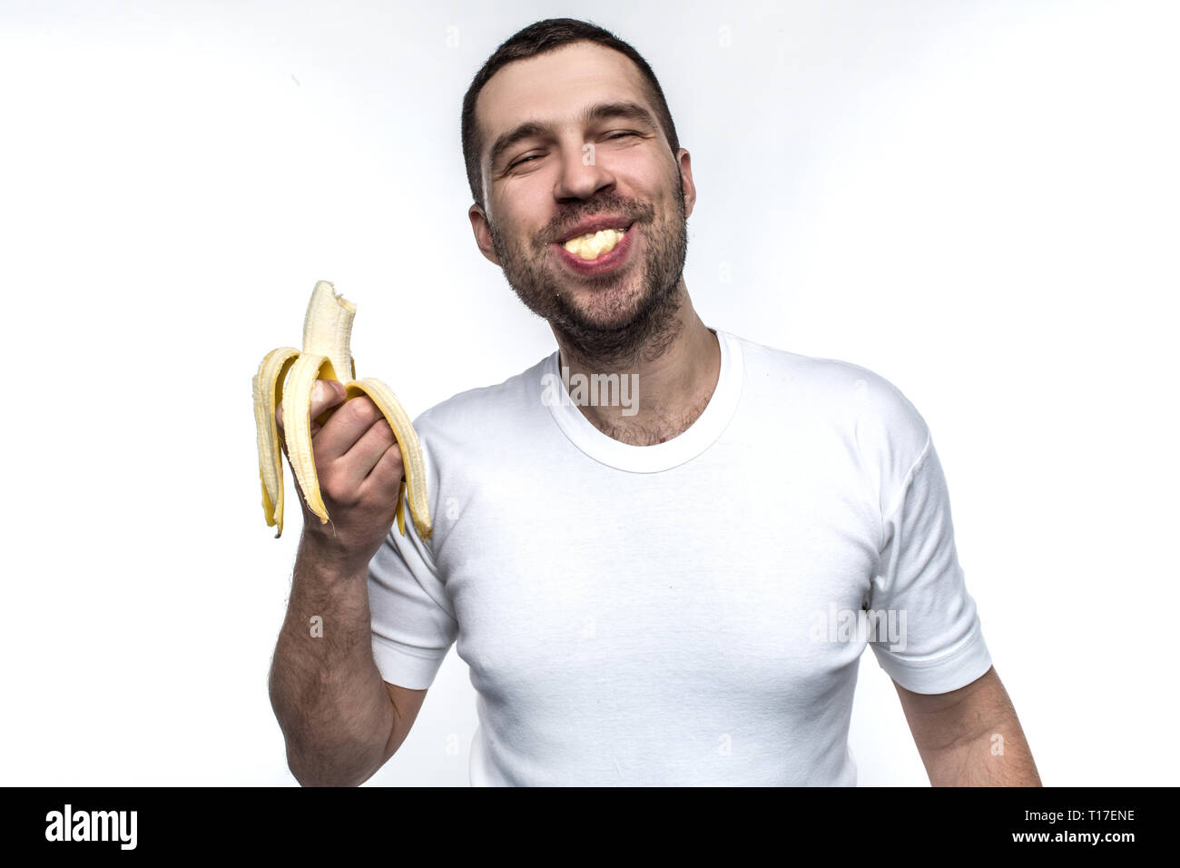 Funny and strange man is eating banana. He is enjoying that. Man is eating banana in a funny manner. His behave is like a small boy has. Isolated on Stock Photo