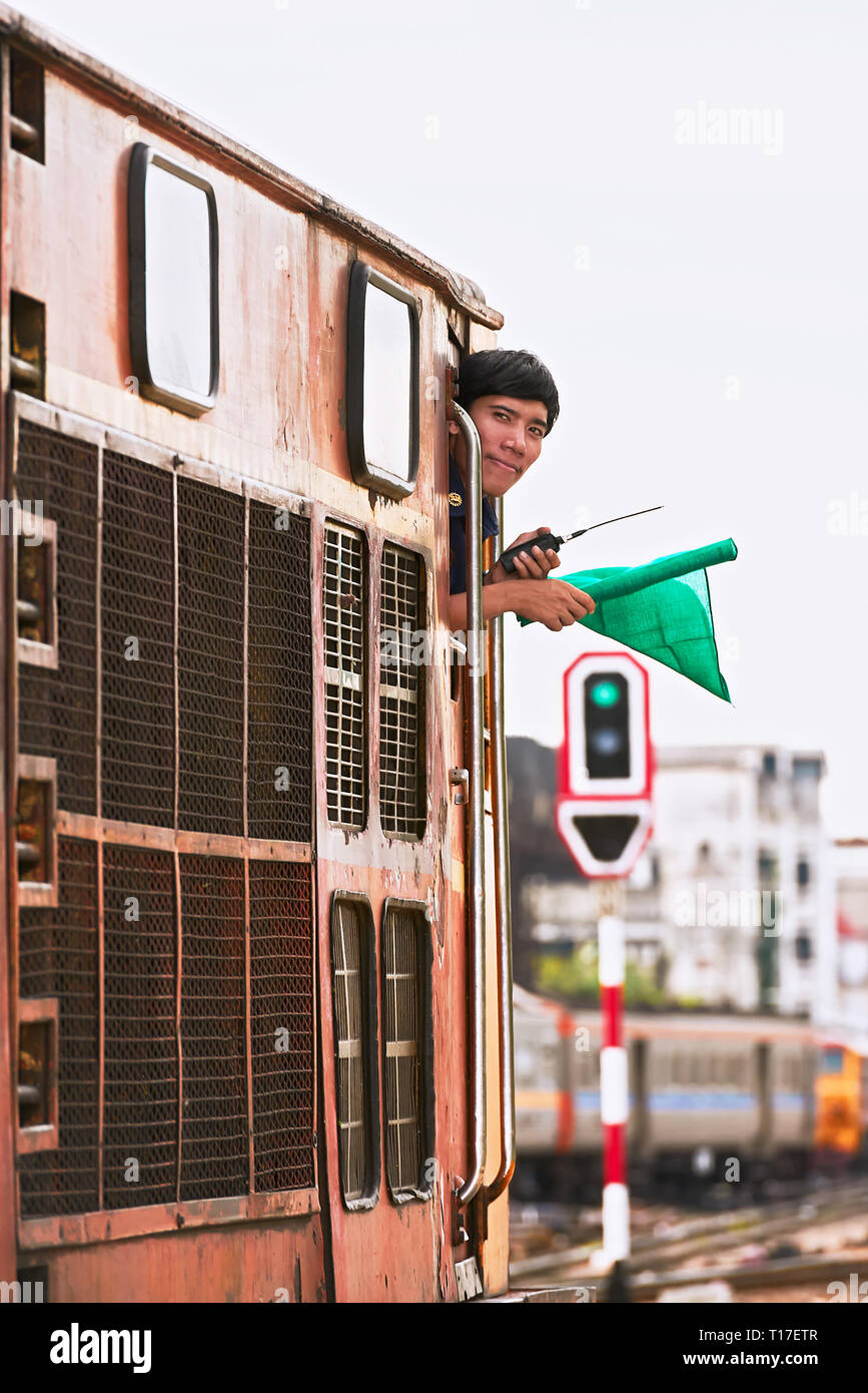 Hualamphong Central Train Station in Bangkok, Thailand - June 14 2011: The driver of a diesel train signaling with a green flag before leaving Stock Photo