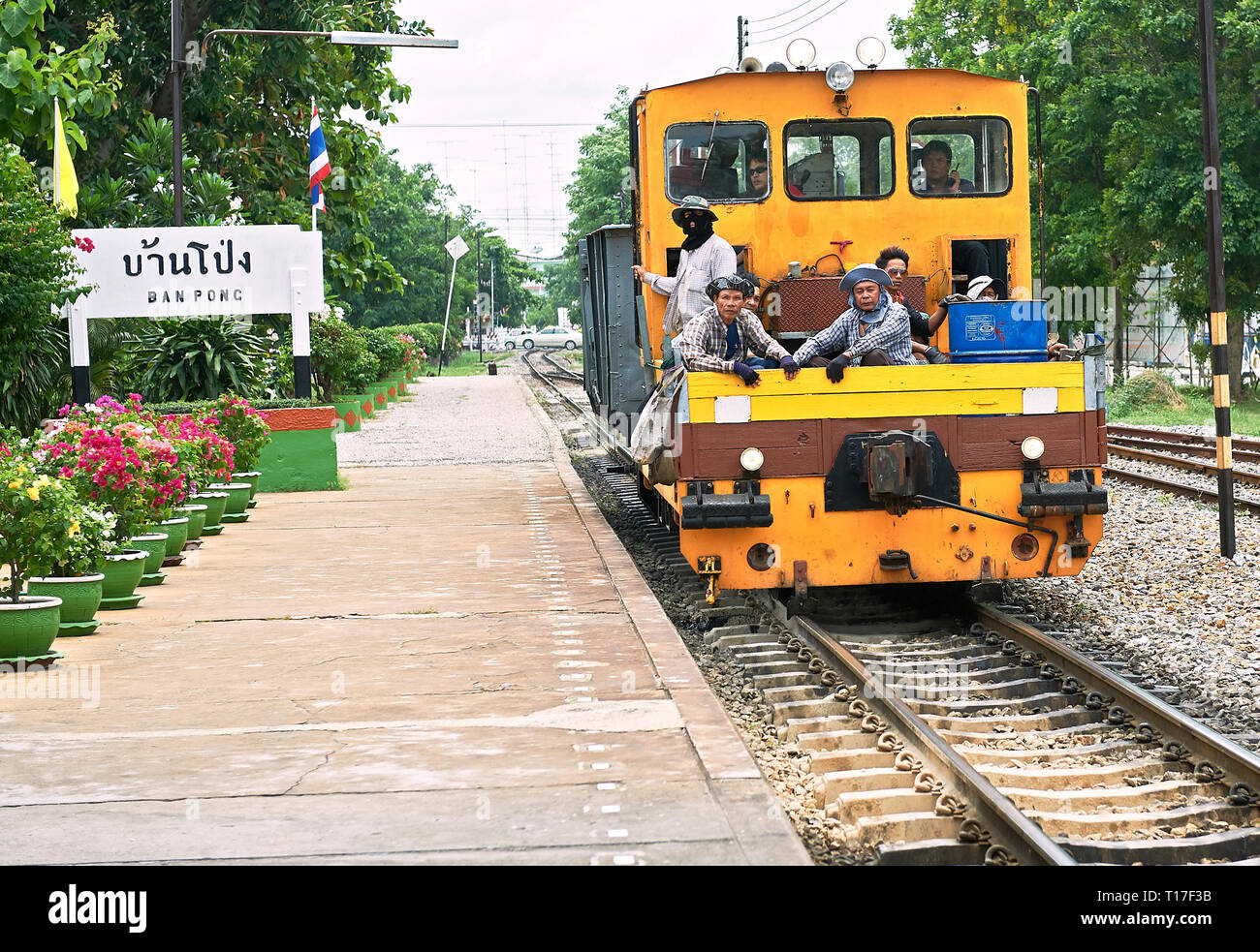 Ban Pong, Thailand: Colorful service train with a group of male employees entering the clean and empty train station Stock Photo