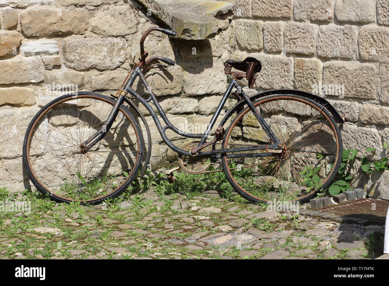 old rusty bicycle parked against a wall Stock Photo