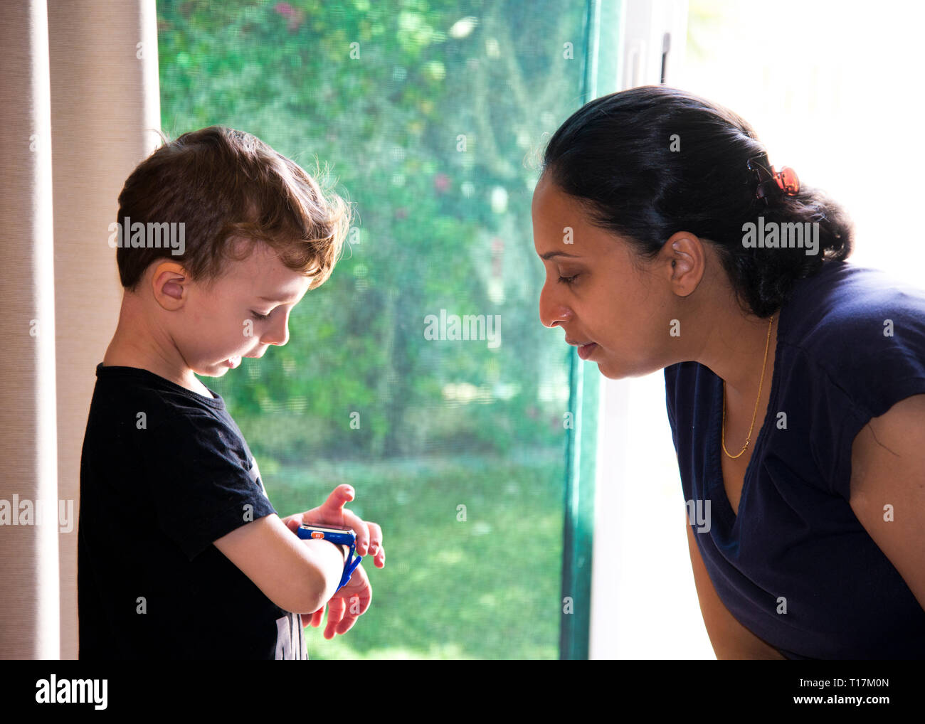 young boy telling the time to from wrist watch parent and teacher,at home Stock Photo