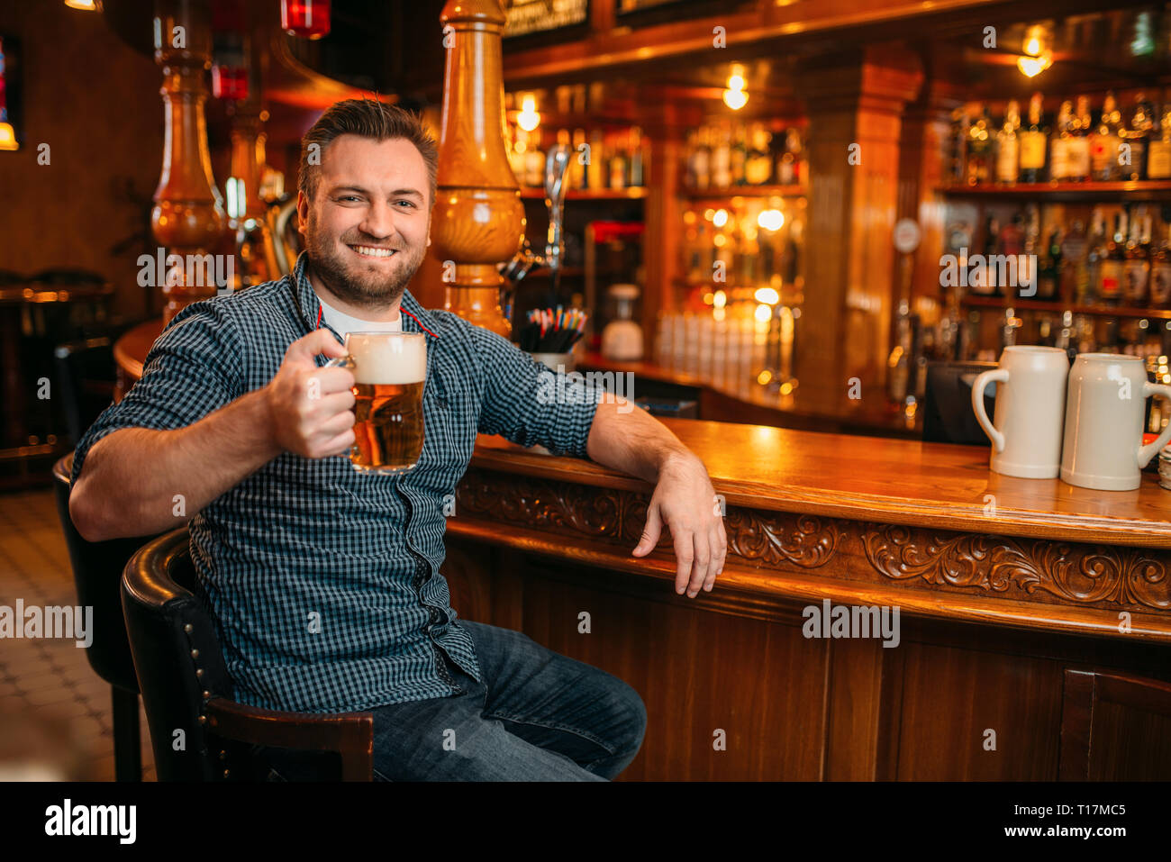 Cheerful man with beer mug at the counter in pub Stock Photo