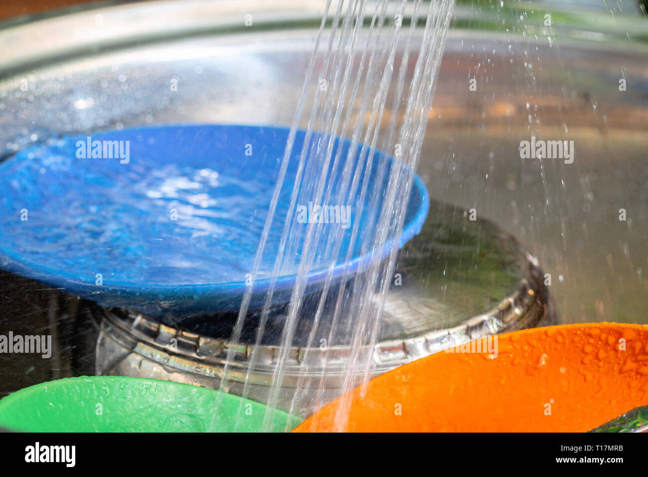 Ware in a metal sink under a stream of water Stock Photo Alamy