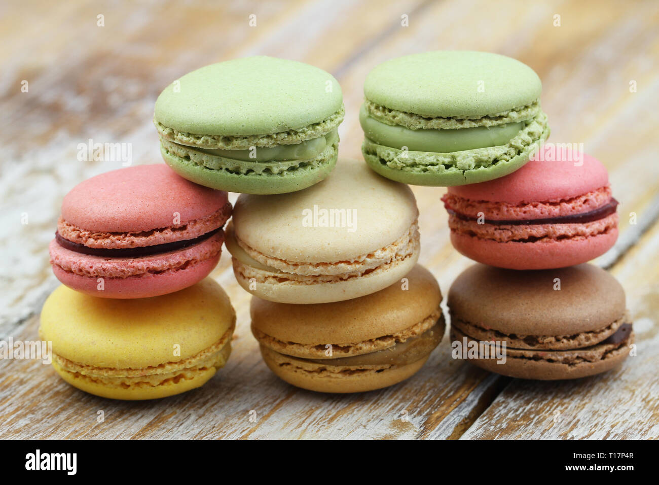 Stack of pistachio, chocolate and raspberry macaroons on wooden surface Stock Photo