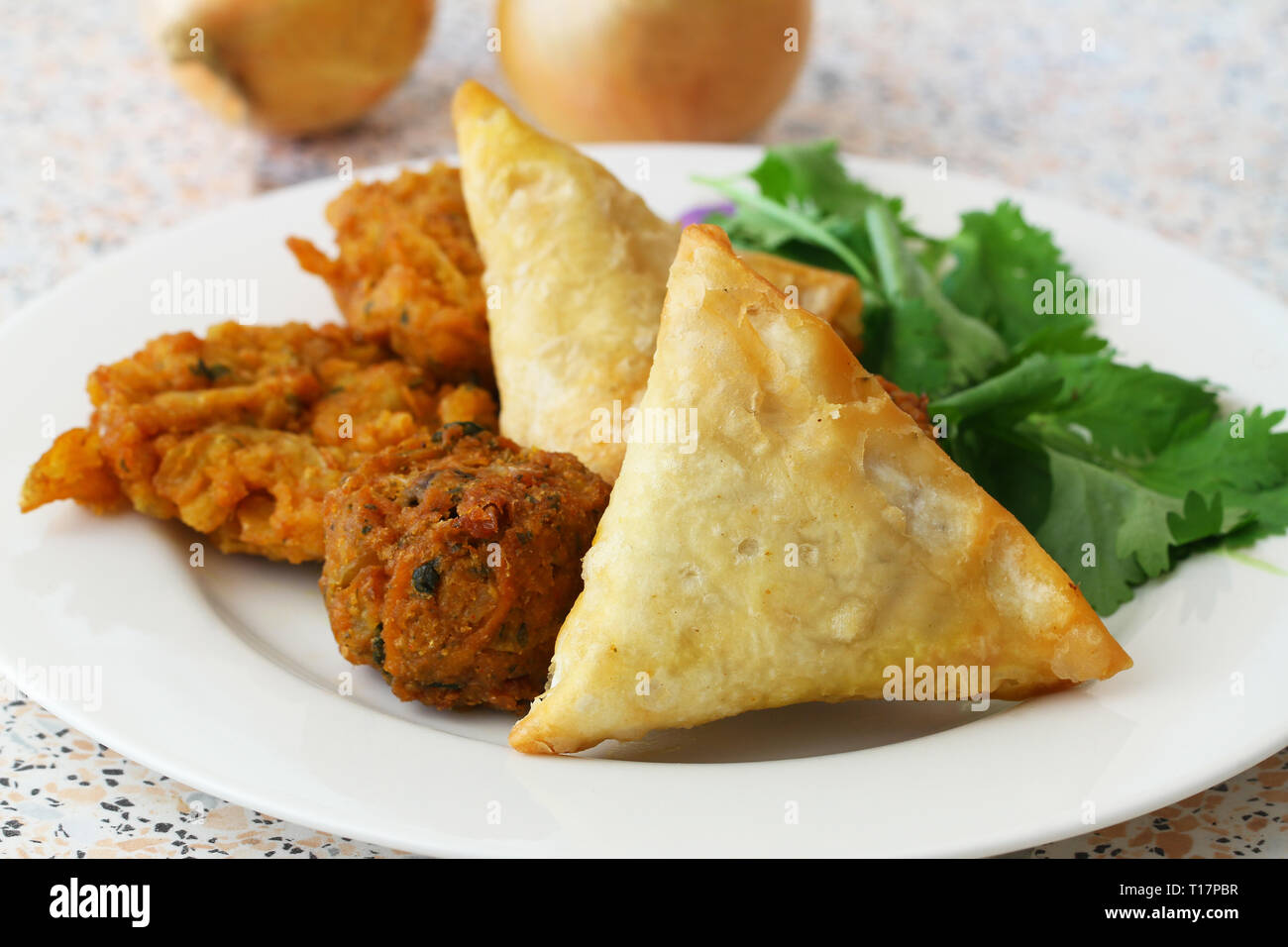 Selection of Indian samosas, onion bhajis and pakoras garnished with