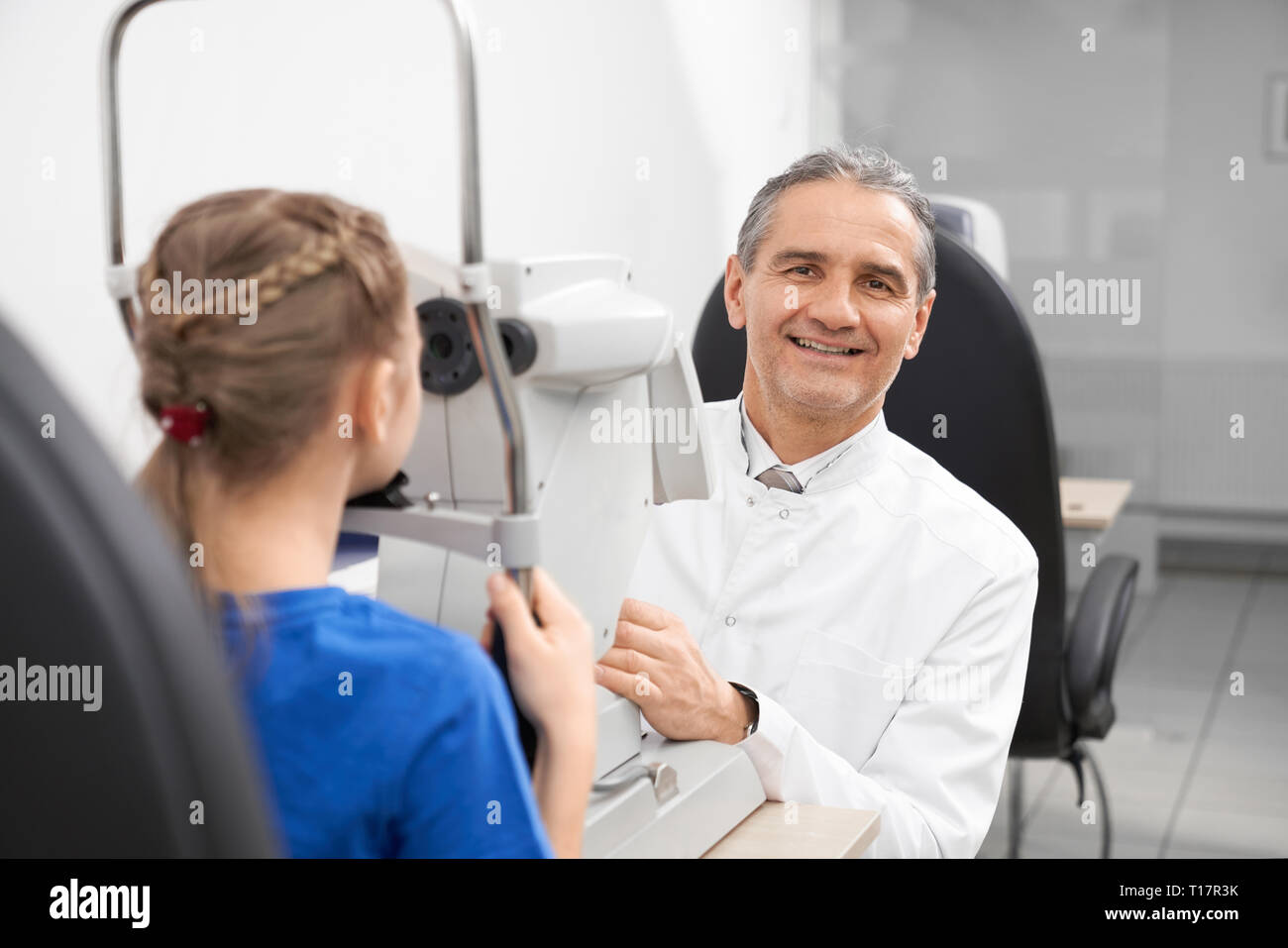 Experienced ophthalmologist doing checkup of eyesight on slit lamp machine. Doctor working on modern special medical equipment in optician clinic. Equipment for examining vision. Stock Photo