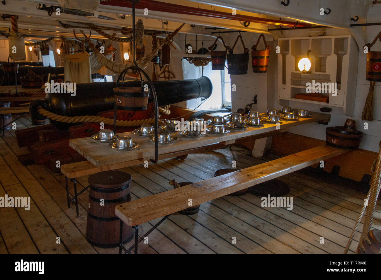 Dining table laid out below deck on the gun deck of HMS Warrior (1860), Portsmouth Historic Dockyard, UK. Stock Photo