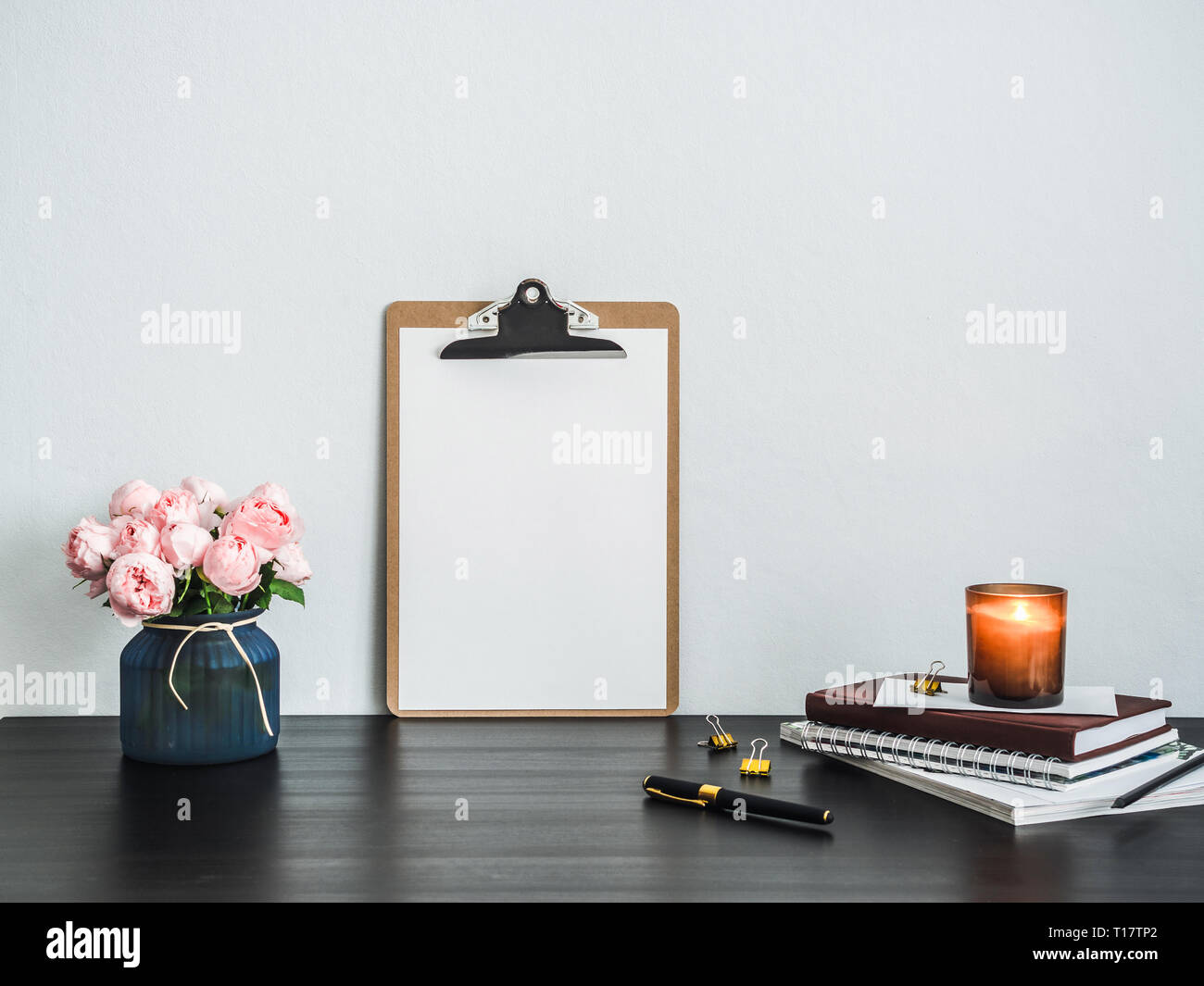 Clipboard with white empty page on table. Clipboard, pink flowers