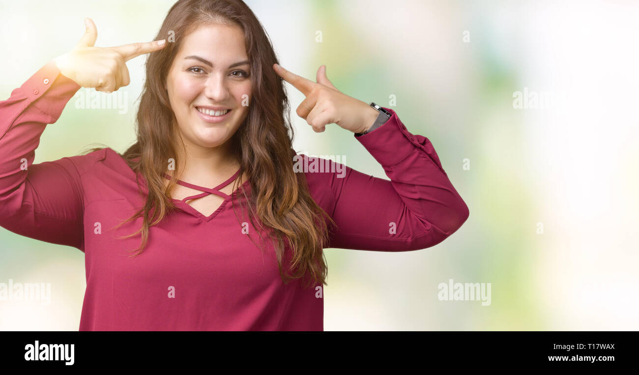 Beautiful plus size young woman over isolated background Smiling pointing to head with both hands finger, great idea or thought, good memory Stock Photo