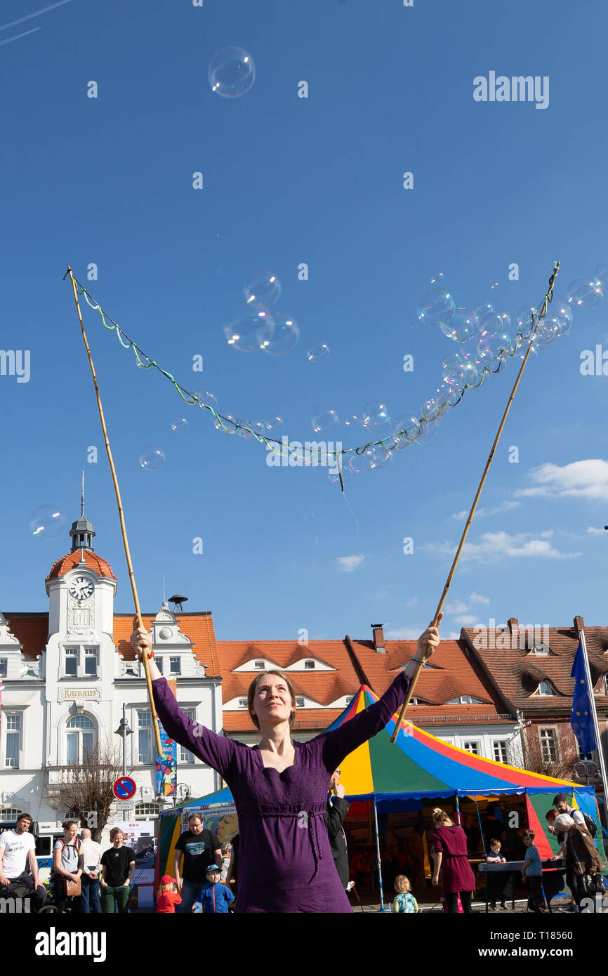 Ostritz, Germany. 23rd Mar, 2019. Tabea Scheinflug (middle) from Görlitz sprays soap bubbles on the market place. The city of Ostritz wants to react to the neo-Nazi festival 'Skinheads Back to the Roots' with a peace festival. Credit: Daniel Schäfer/dpa/Alamy Live News Stock Photo