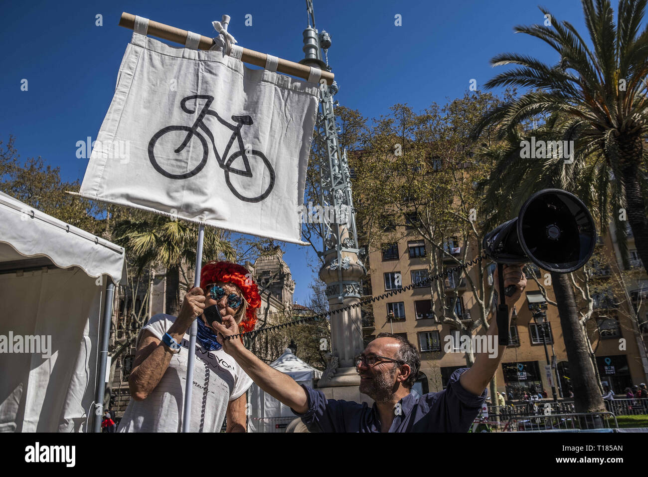 Barcelona, Catalonia, Spain. 24th Mar, 2019. A man wearing a wig is seen speaking on a megaphone while holding a banner during the event.Thousands of people have participated in the Bicicletada Popular 2019 (Popular bike ride) organized by the City Council in order to encourage the use of bicycles in Barcelona. Credit: Paco Freire/SOPA Images/ZUMA Wire/Alamy Live News Stock Photo