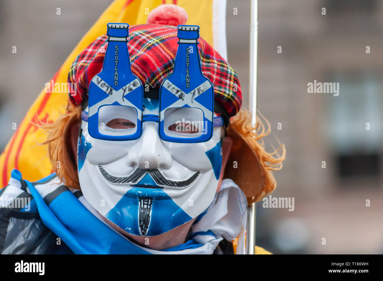 Glasgow, Scotland, UK. 24th March, 2019. A man wearing a mask and a See You Jimmy hat joins campaigners in support of Scottish Independence as they gather for a rally in George Square.The rally was organised by the group Hope Over Fear. Credit: Skully/Alamy Live News Stock Photo