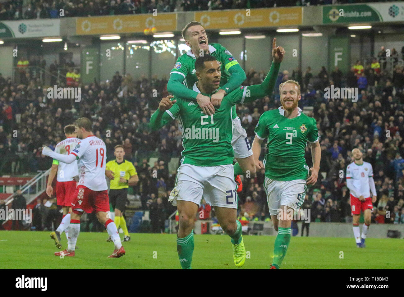 National Football Stadium at Windsor Park, Belfast, Northern Ireland. 24  March 2019. UEFA EURO 2020 Qualifier- Northern Ireland v Belarus. Action from tonight's game. Josh Magennis  (21) celebrates his winner for Northern Ireland with Steven Davis (8) and Liam Boyce (9). Credit: David Hunter/Alamy Live News. Stock Photo