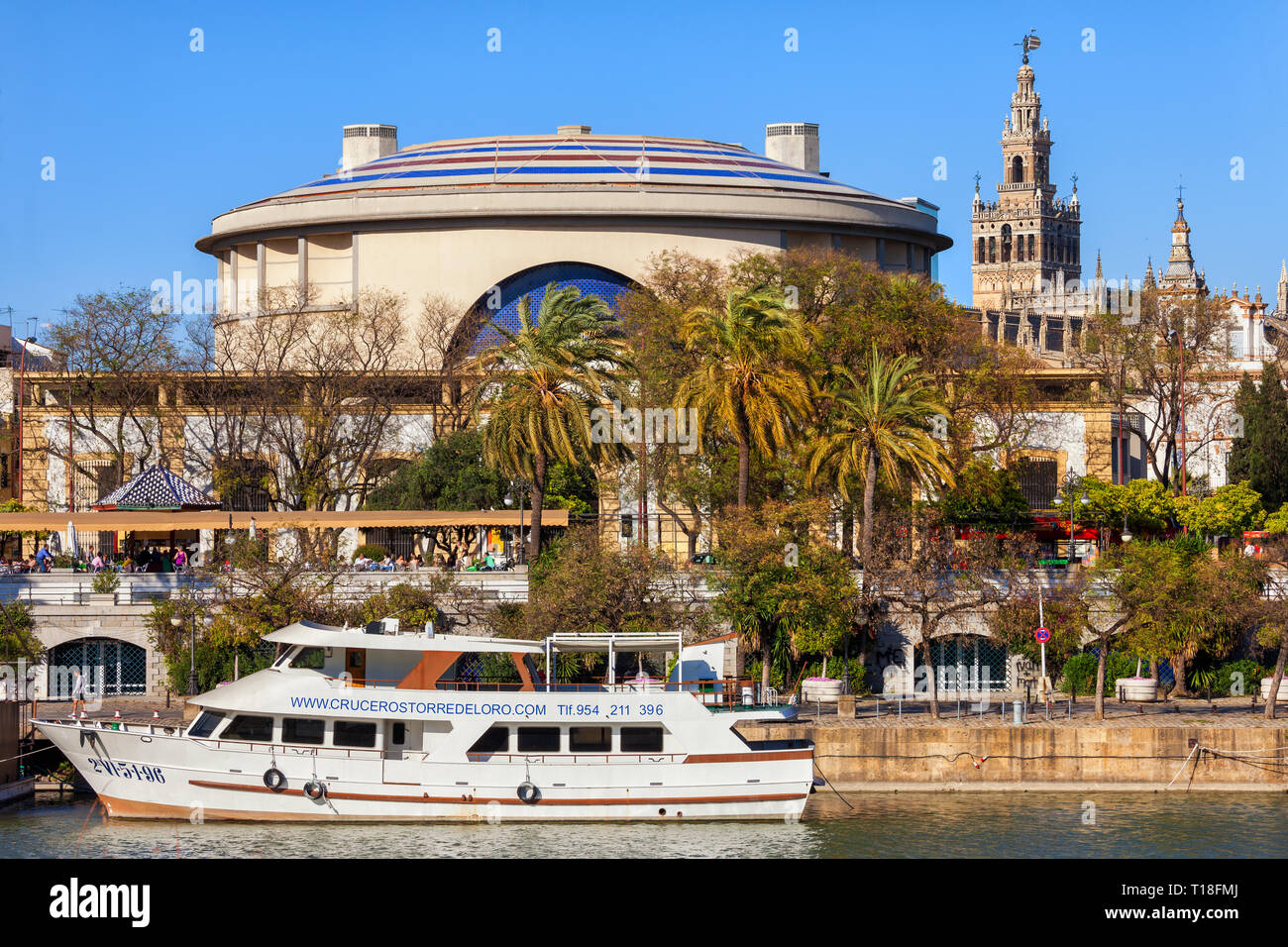 Spain, city of Seville, Teatro de la Maestranza theater and opera house, tour boat on Guadalquivir river, La Giralda bell tower of the Cathedral in th Stock Photo