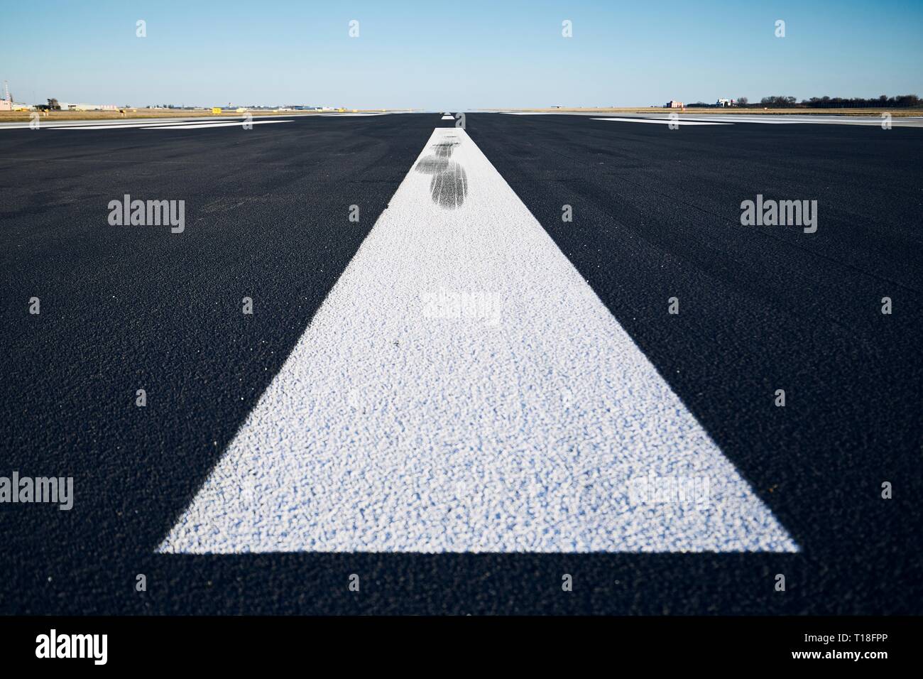 Surface level of airport runway with road marking against clear sky. Stock Photo