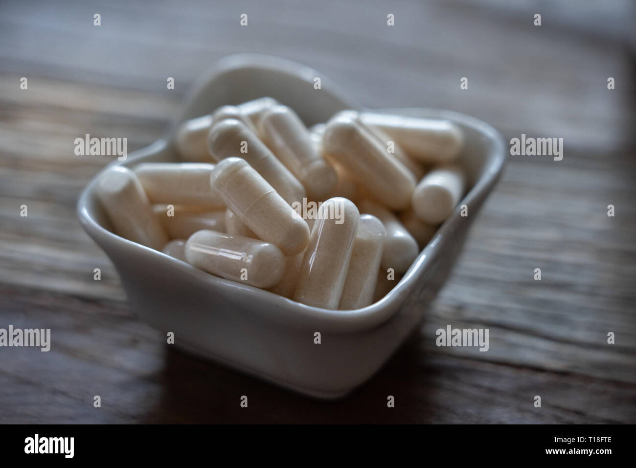 vitimin pills piled into a small porcelain bowl Stock Photo