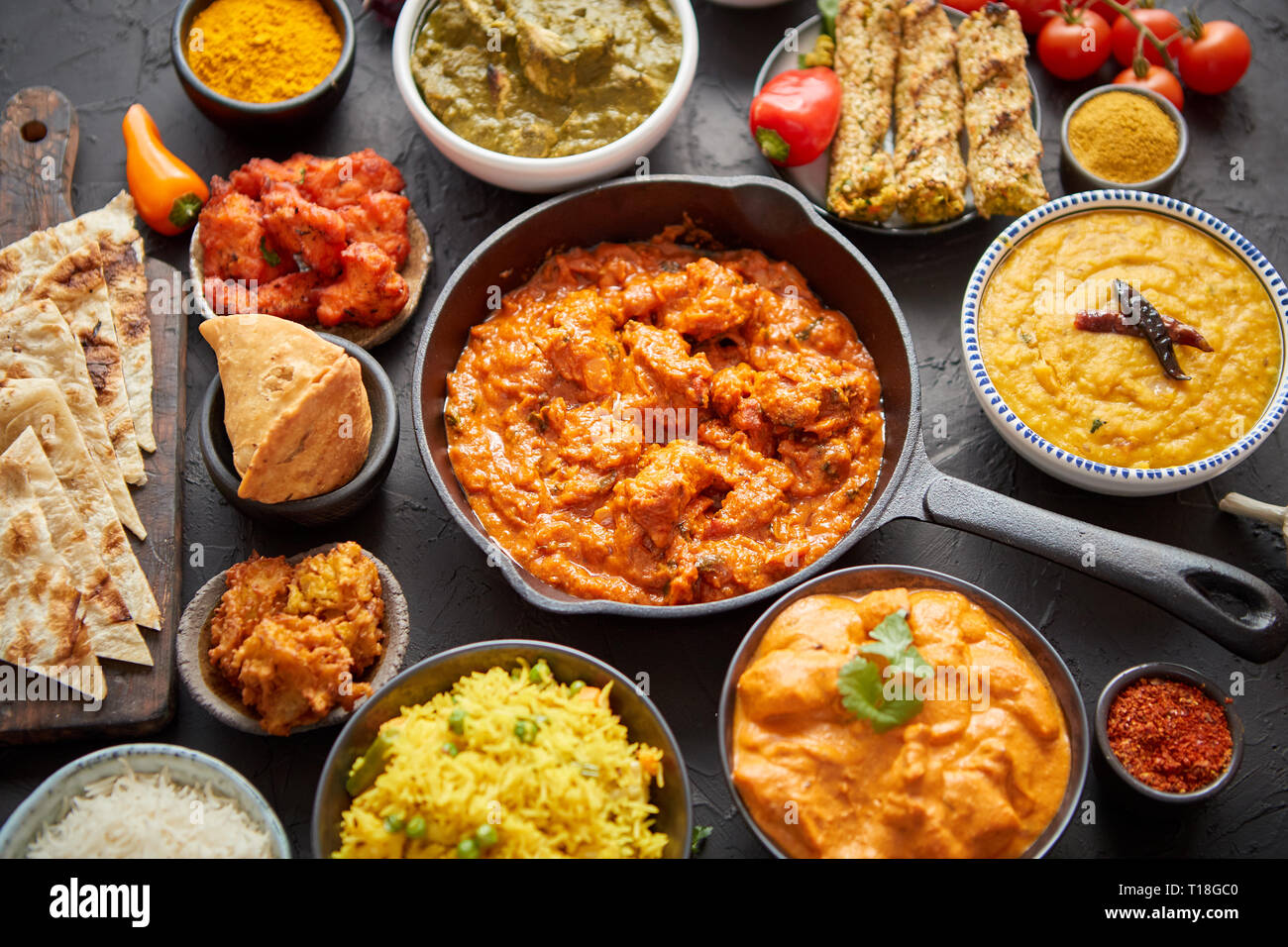 Various Indian dishes on a table. Spicy chicken Tikka Masala in iron