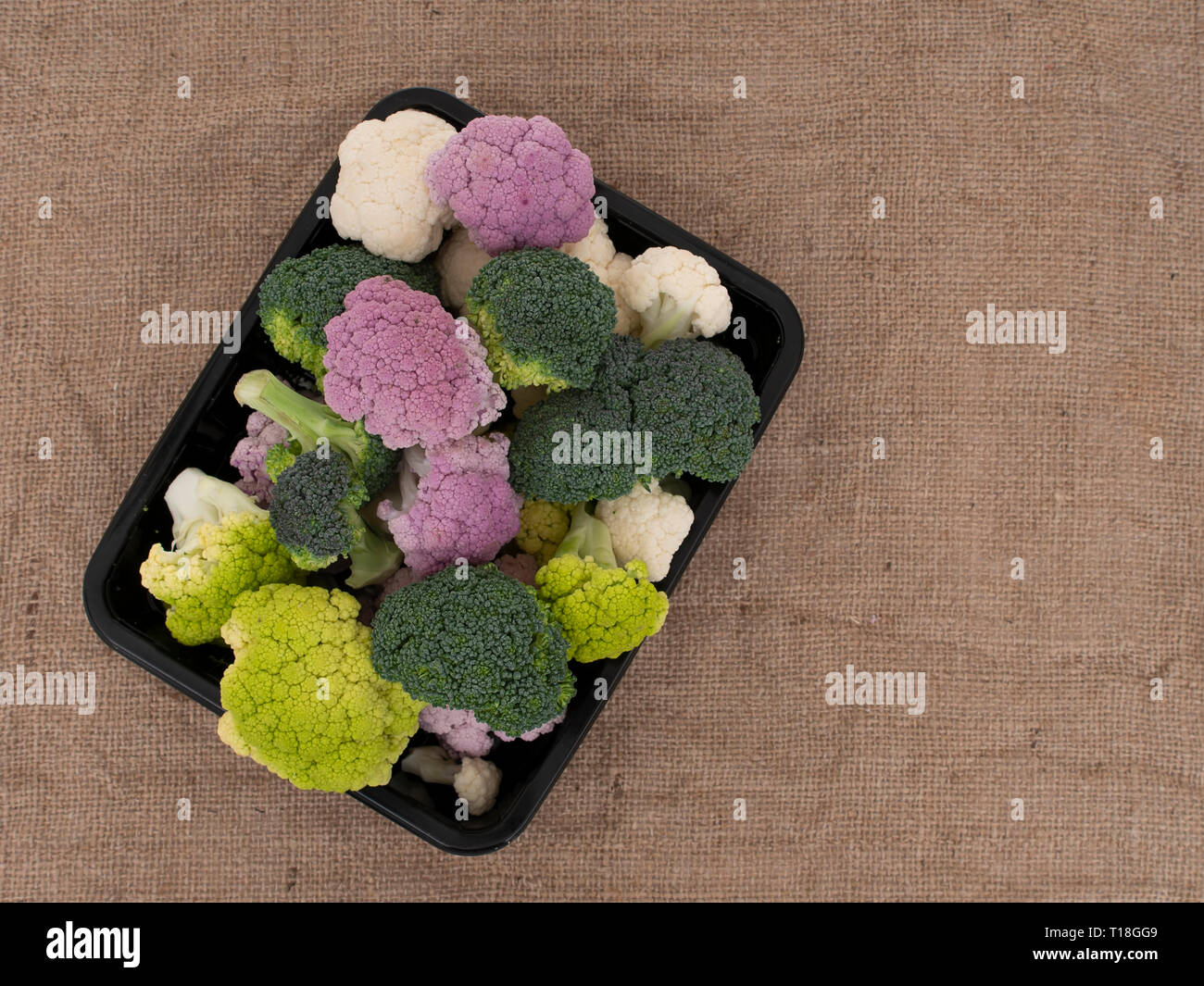 Colourful vegetables, on hessian with copyspace. Raw purple, white and green cauliflower with broccoli florets. Healthy assortment. Stock Photo