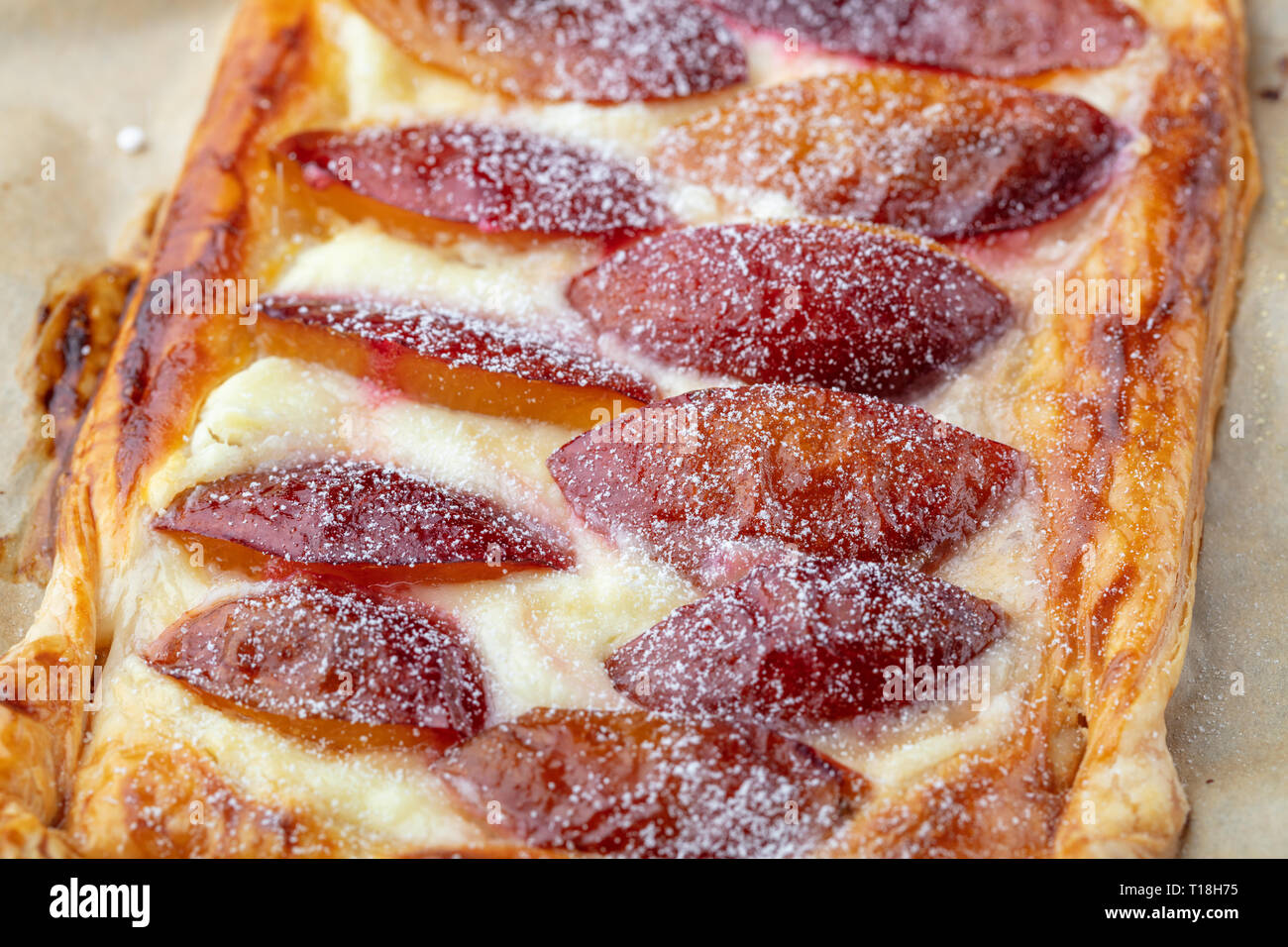Homemade puff pastry flan with plums, close up. Delicious rectangular