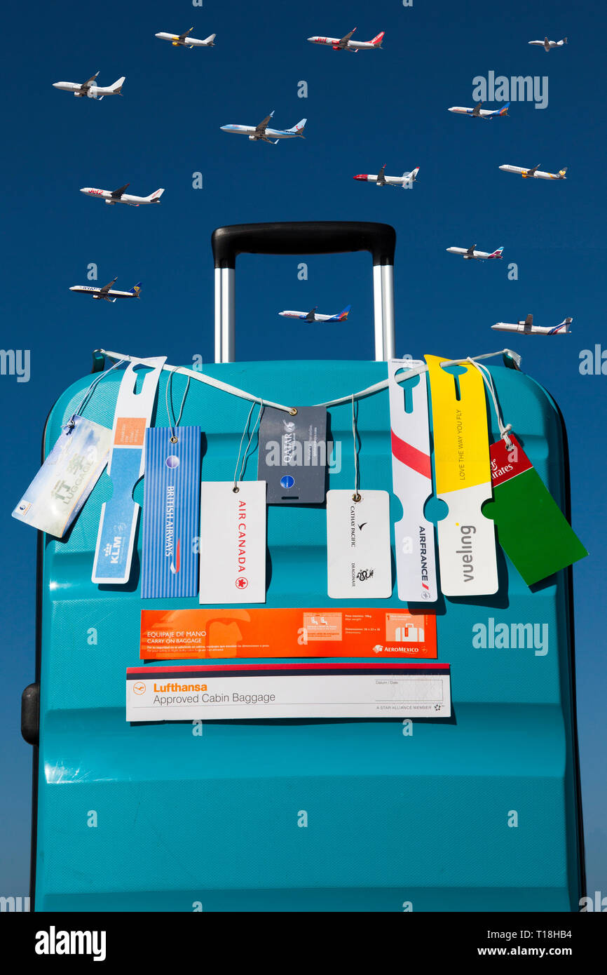 Trolley with hand luggage tags of different airlines over a blue sky with several airplanes Stock Photo