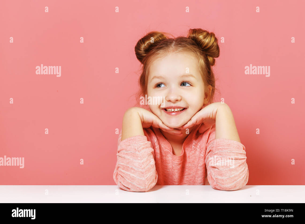 Close-up portrait of nice lovely attractive fascinating winsome cheerful little child girl with buns looking up aside over pink background Stock Photo