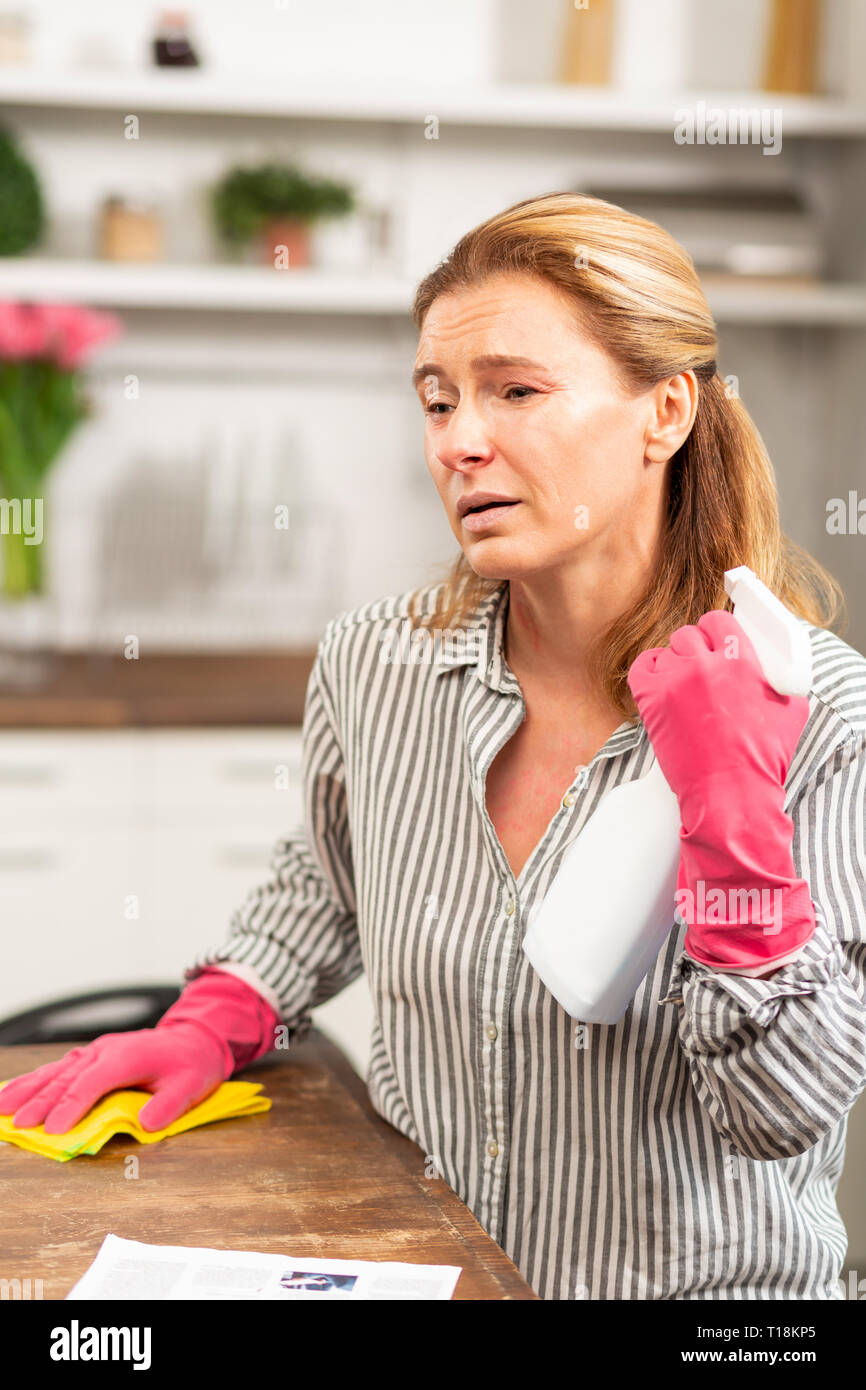 Darkeyed mature woman feeling really sick cleaning apartment Stock