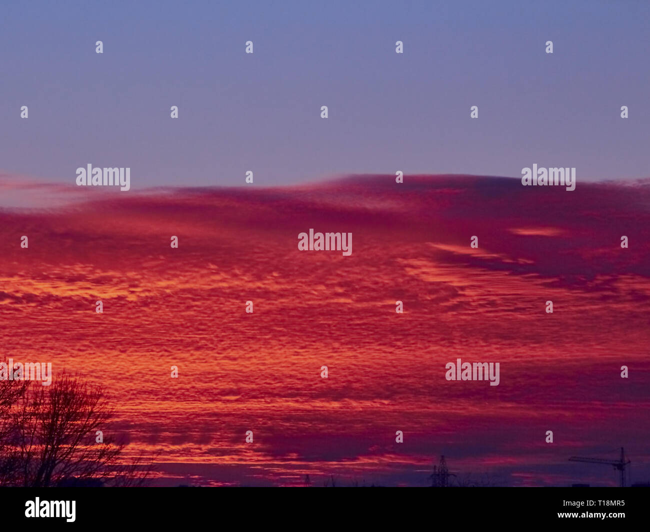 Sunset with red stratus clouds and blue sky with flying white plane ...