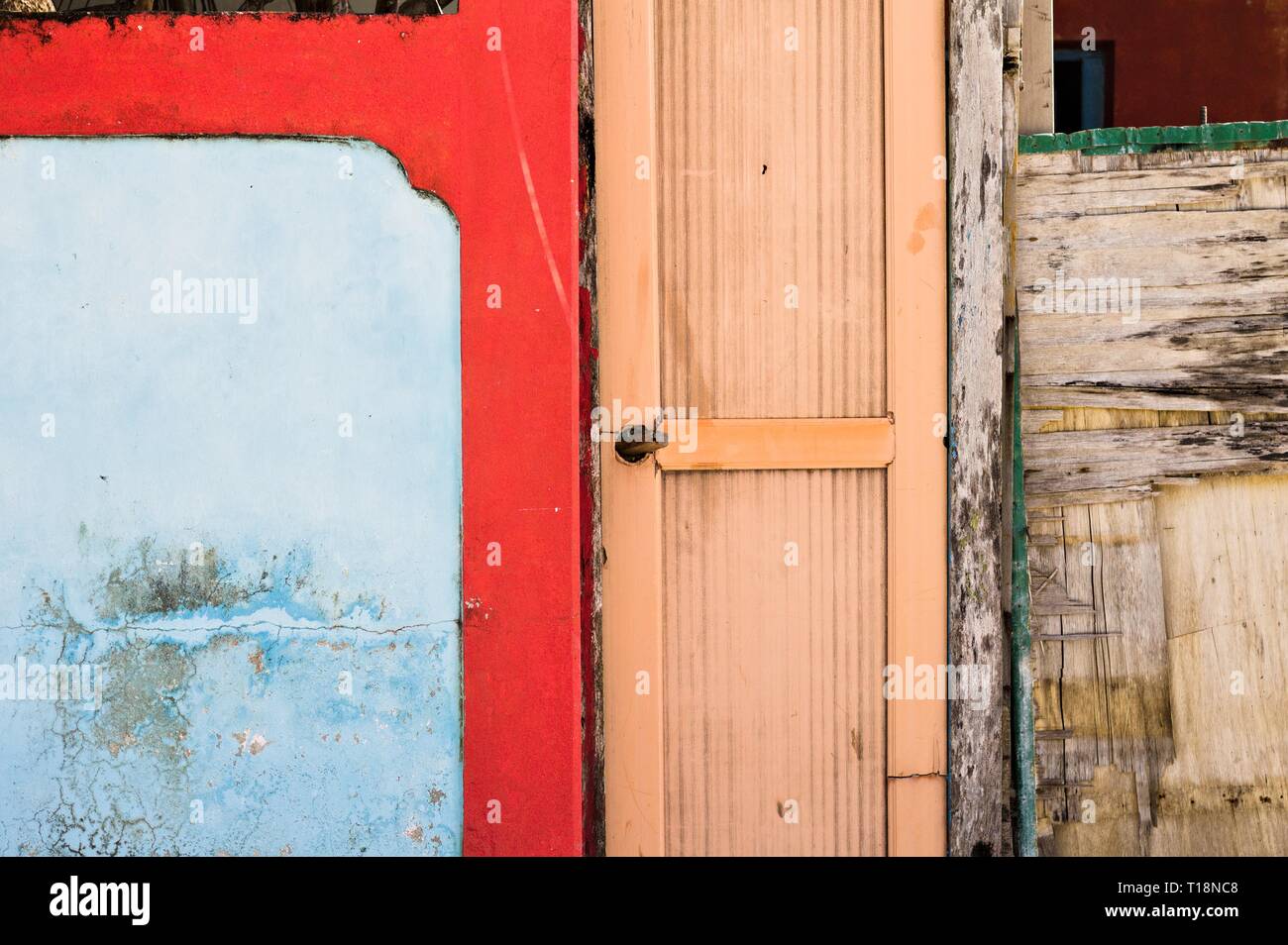 Wooden door of an abandoned house with a red and blue wall (Ar Atoll ...