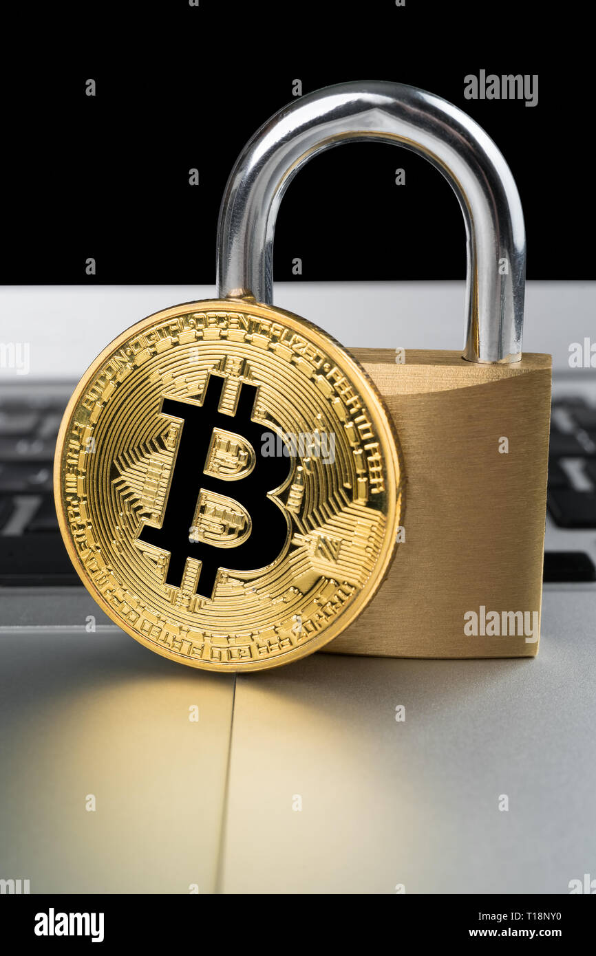 Physical bitcoin with padlock on a laptop computer keyboard. Cyber ...