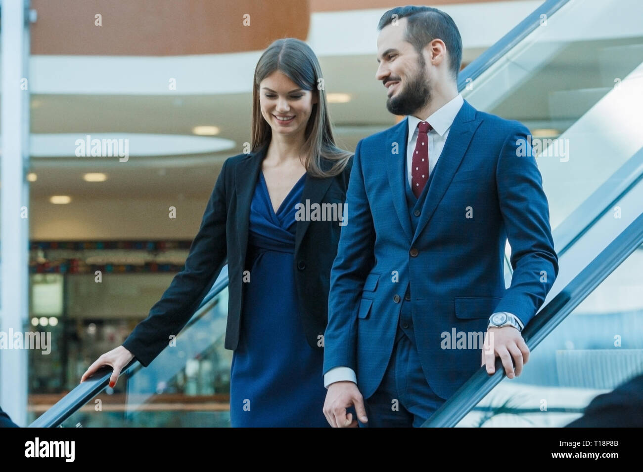 Business couple on escalator talking and smiling Stock Photo