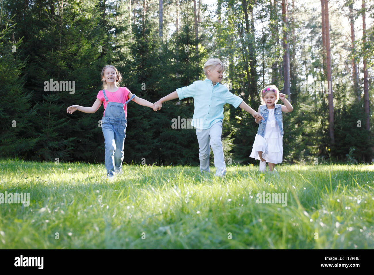 Group of young children running towards camera in park Stock Photo
