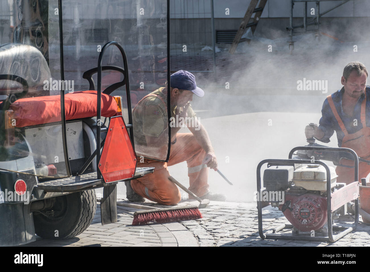 Krakow, Poland - September 21, 2019: Road workers at asphalt roadway street patching reaparing work while smokes a cigar Stock Photo