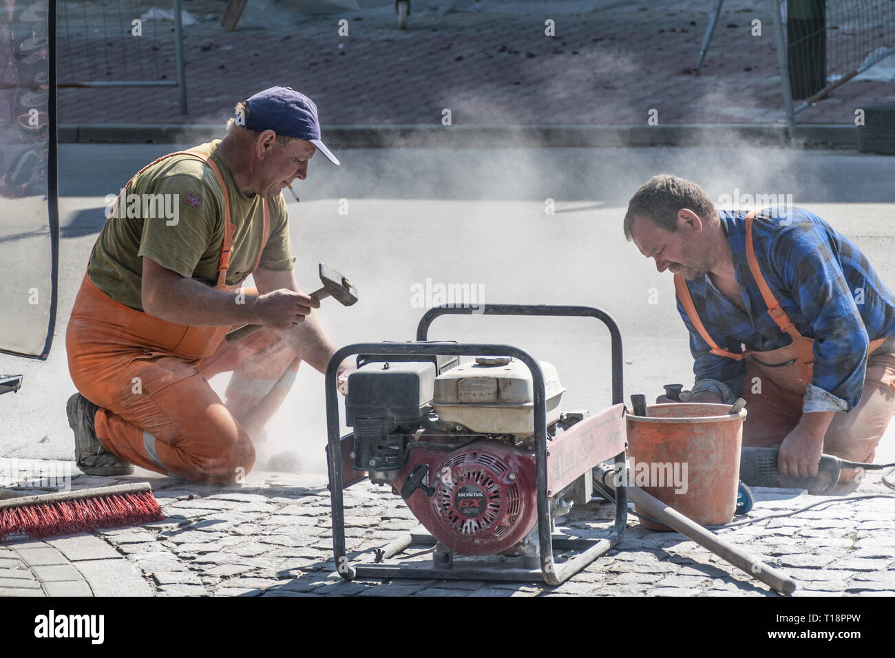 Krakow, Poland - September 21, 2019: Road workers at asphalt roadway street patching reaparing work while smokes a cigar Stock Photo