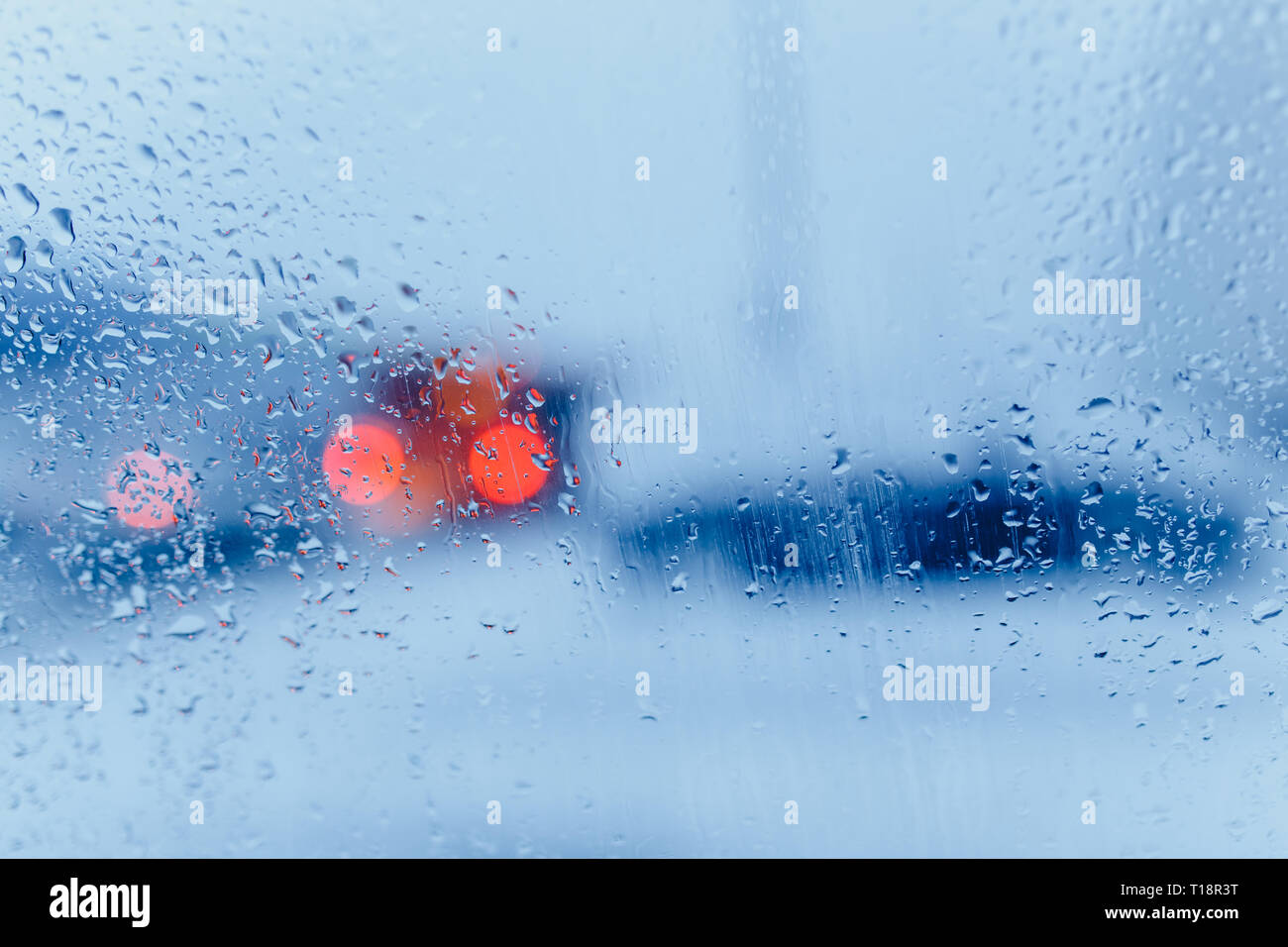 Traffic abstract in rain. Traffic seen from inside a car. Rain drops on windshield and car tail lights in bokeh Stock Photo