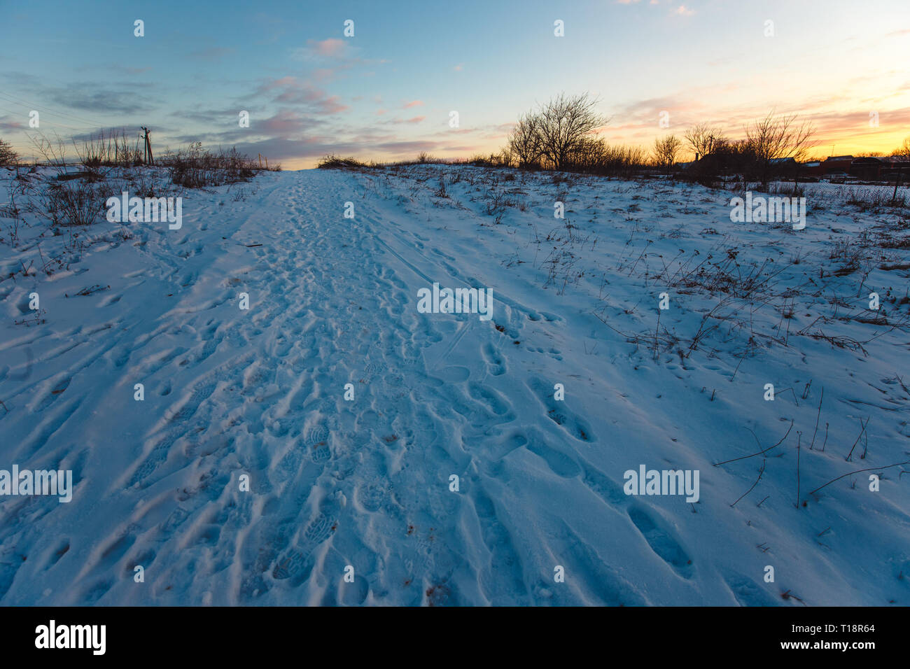 Snowy pathway countryside at sunset Stock Photo