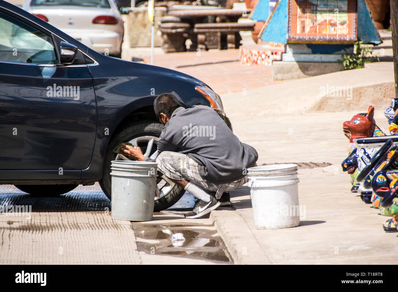 A young boy cleaning the hub caps of a car, Ensenada, Mexico Stock
