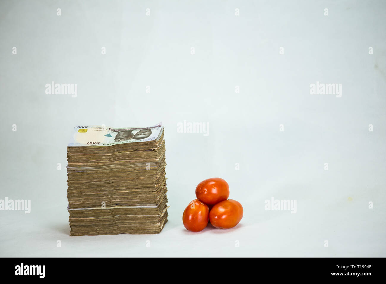 Stack of nigeria naira notes on white background wit tomatoes Stock Photo