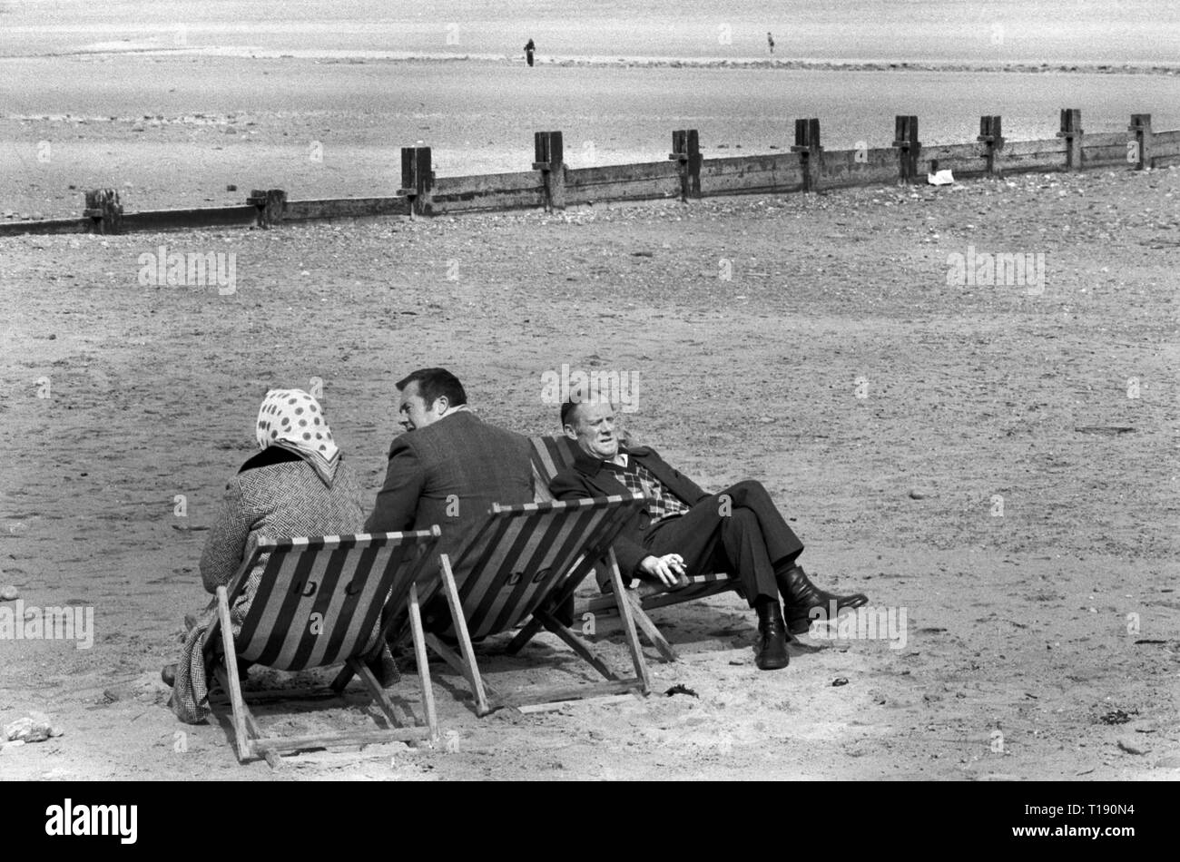 Peel Isle of Man 1970s. Older group of people on the beach sitting on deckchairs facing different ways, but still able to talk. 1978 HOMER SYKES Stock Photo