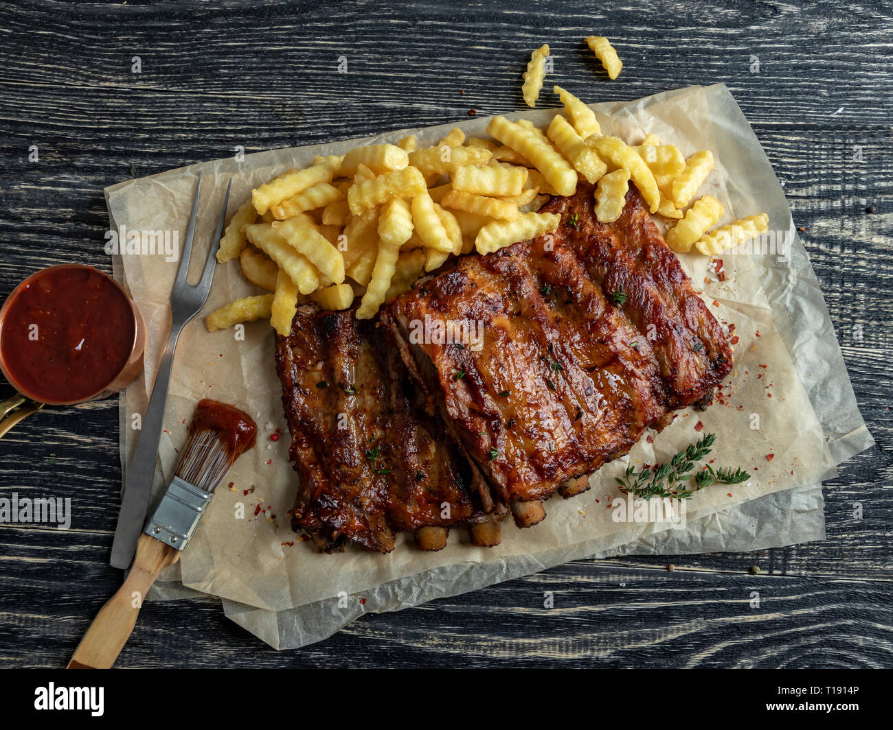 grilled roast pork ribs with sauce , french fries, spices, wooden background Stock Photo