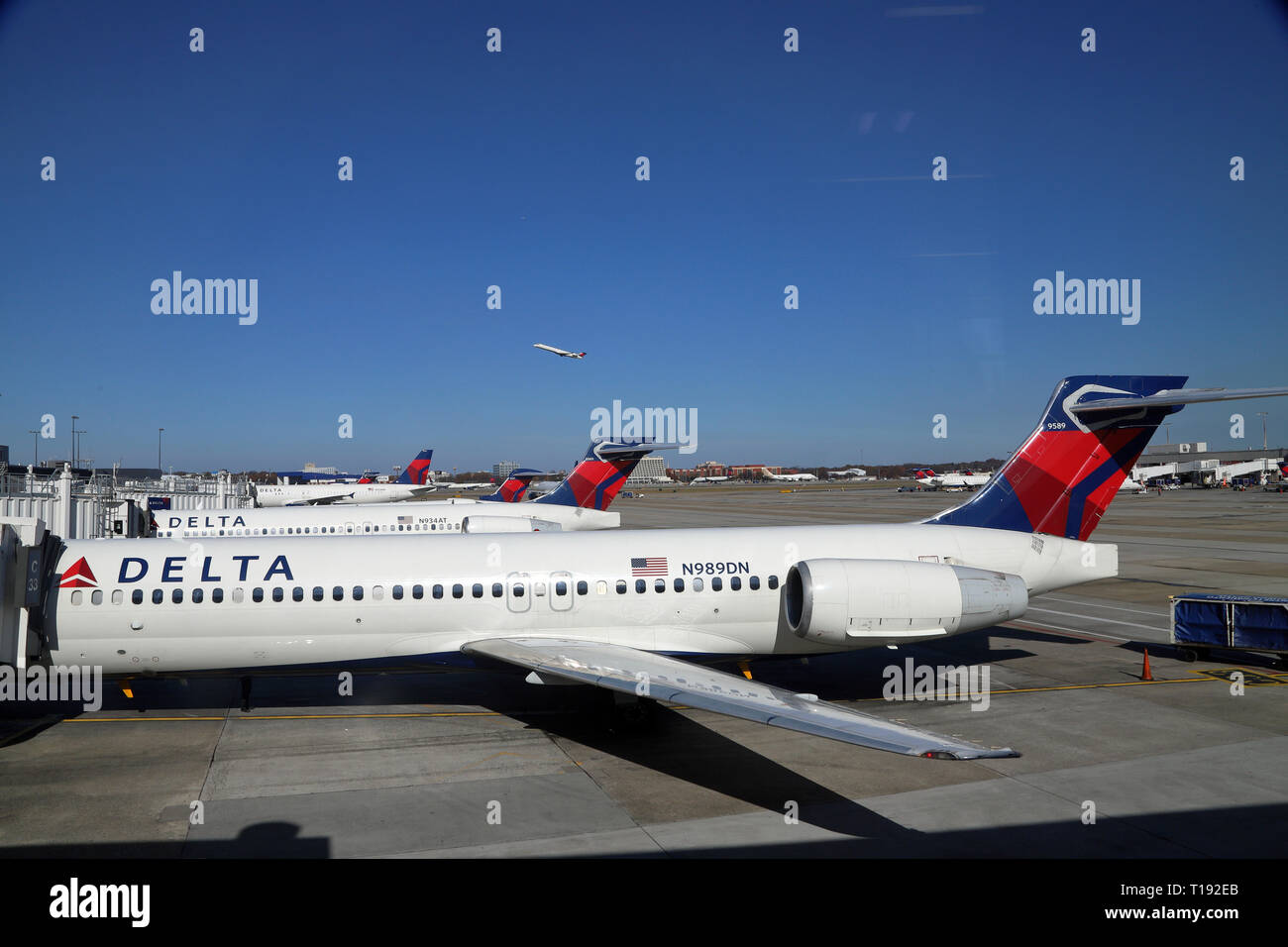 Atlanta, GA / USA - December 2, 2018: Delta planes at the C terminal of Hartsfield-Jackson Atlanta International Airport, with plane in sky in the bac Stock Photo