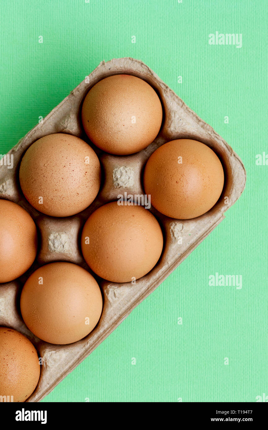 Raw hen eggs in a carton with a colourful background. Stock Photo
