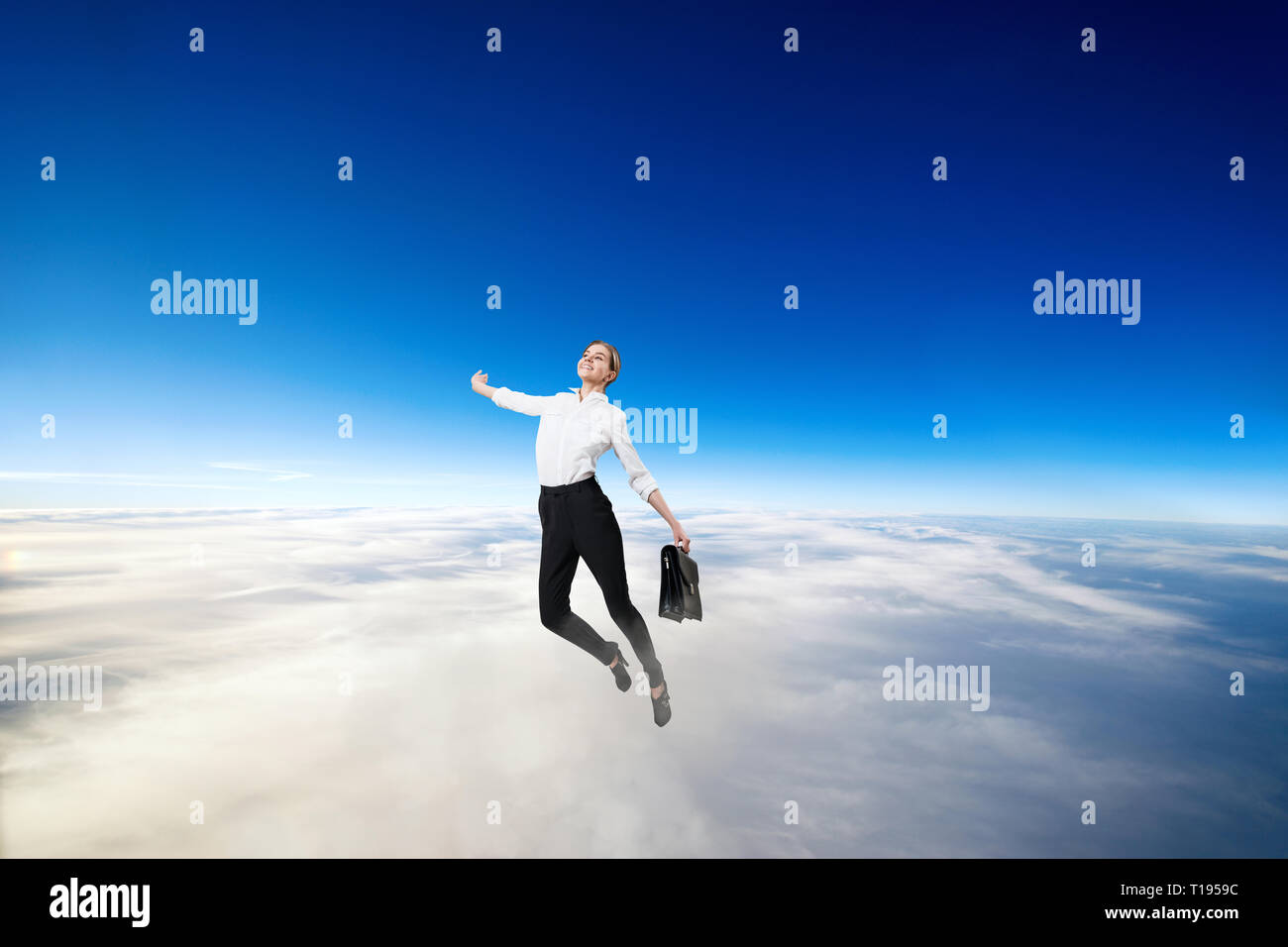 Businesswoman in formal wear flying in blue sky. Stock Photo