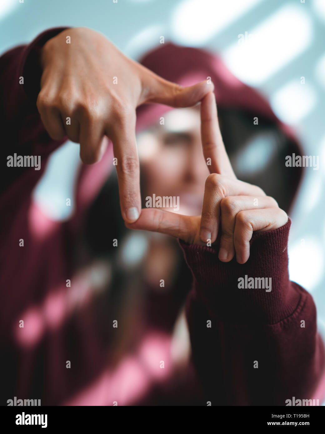 Woman showing framing hand gesture on bright background. Stock Photo