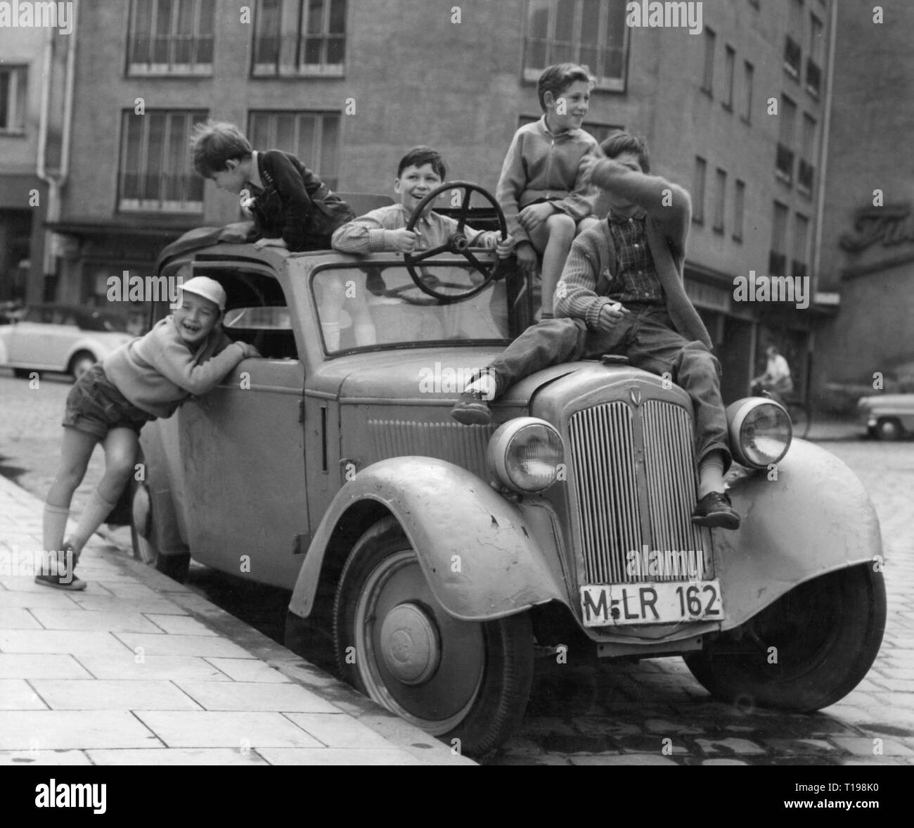 people, children, playing, boys with old DKW car, Munich, circa 1950, Germany, childhood, infancy, half-length, half length, standing, sitting, sit, a ripple of laughter, laugh, laughing, fun, cap, caps, steering wheels, adjustable steering wheel, car, cars, DKW F8, street, streets, 20th century, 1950s, children, child, kids, kid, playing, play, boys, boy, historic, historical, boy, boys, male, people, Additional-Rights-Clearance-Info-Not-Available Stock Photo
