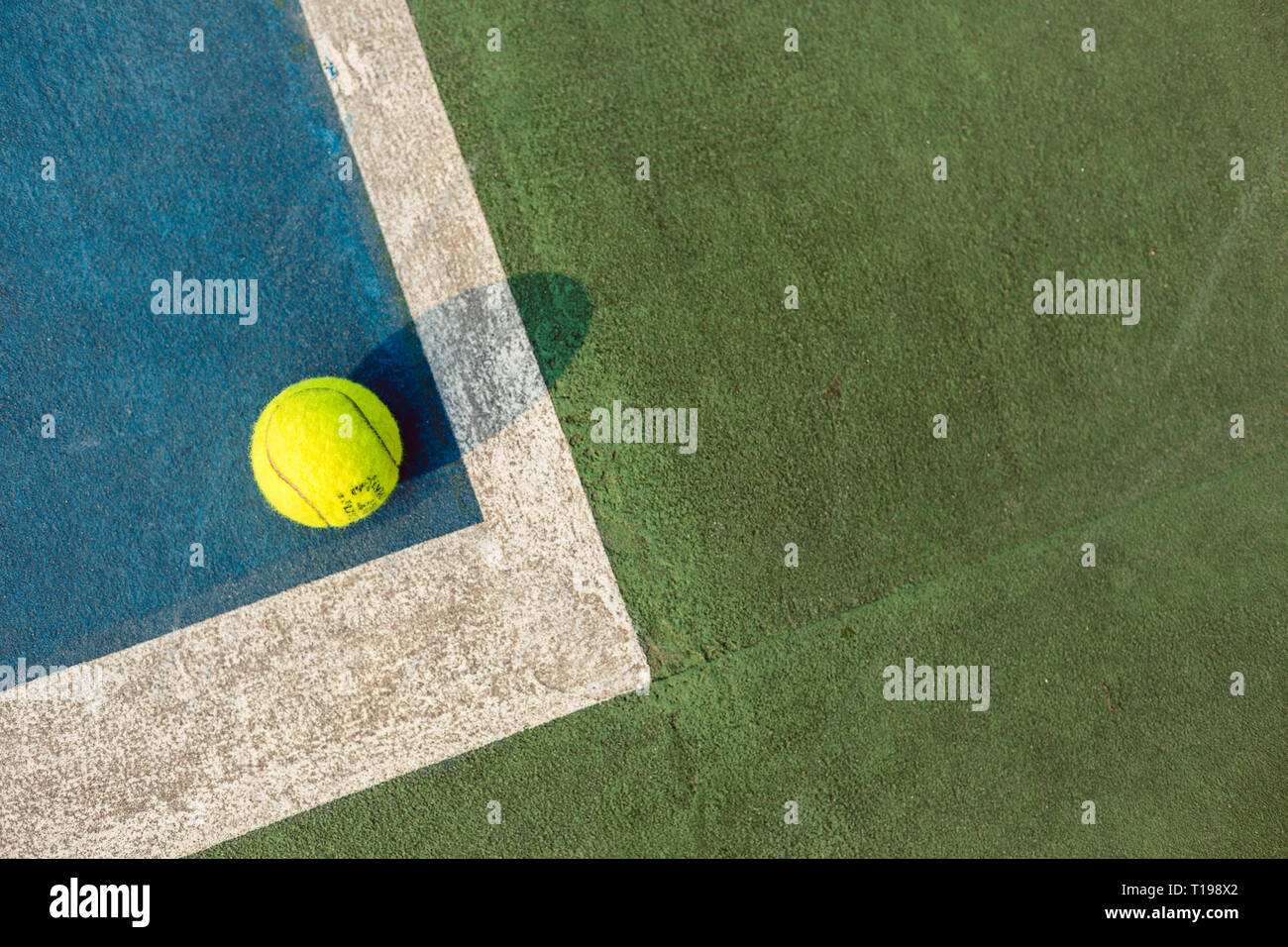 Fluorescent yellow tennis ball in the corner on blue acrylic surface Stock Photo