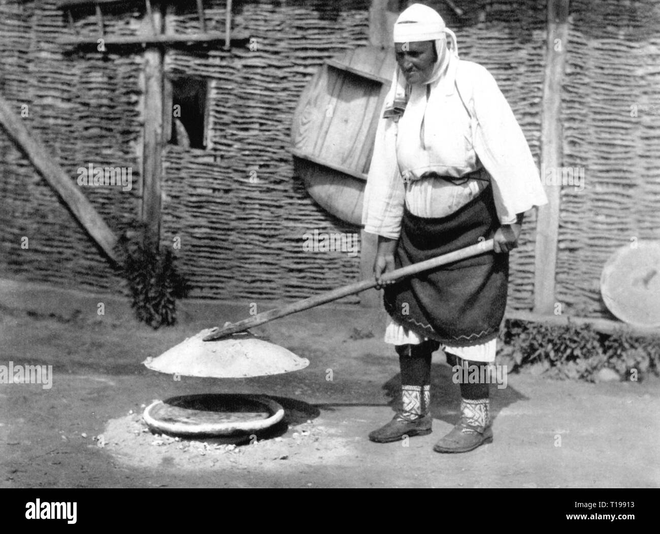 geography / travel historic, Albania, people, an old woman is baking bread, region around Mamurras, Atlantis, number 10, 1930, Albanians, immigrated from the Kosovo, immigrant, immigrants, Kosovians, agriculture, farming, country life, bowl, bowls, ash, ashes, ash heap, foodstuff, food, handwork, handiwork, handiworks, Mamurrasi, ethnicity, ethnic, ethnical, ethnicities, full-length, full length, female, national costume, national costumes, folklore, Kingdom of Albania, the Balkans, Balkan Peninsula, Europe, 20th century, 1930s, woman, women, bak, Additional-Rights-Clearance-Info-Not-Available Stock Photo